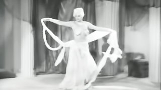 Attractive brunette wearing a turban and white colored dress with sparkles have a nasty dance on a stage