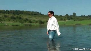 Clothed slut sensually touching wet body in the lake