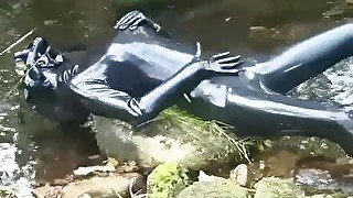 Outdoor walk in the wood and river bath full encased in black latex catsuit and rubber gas mask