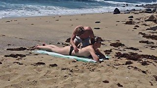 Fille qui bronze seins nus se fait baiser à la plage sur le sable, Naemyia