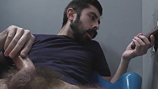 Bearded white man sucking and fucking a black cock at a gloryhole
