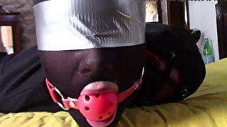 Slave girl lays on the floor wearing a ball-gag and high heels